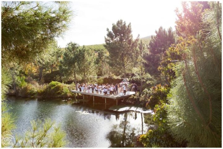 Wedding guests gathered on a timber deck over the pond, surrounded by pines, Old Mac Daddy, Elgin Valley