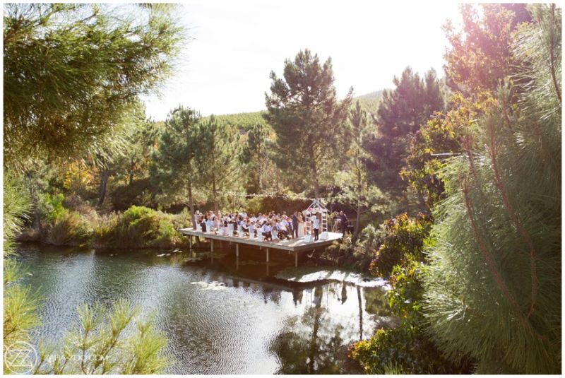 Wedding guests gathered on a timber deck over the pond, surrounded by pines, Old Mac Daddy, Elgin Valley