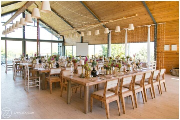 The Barn set for a wedding reception with long tables, flowers and a curtain of fairy lights, Old Mac Daddy, Elgin Valley