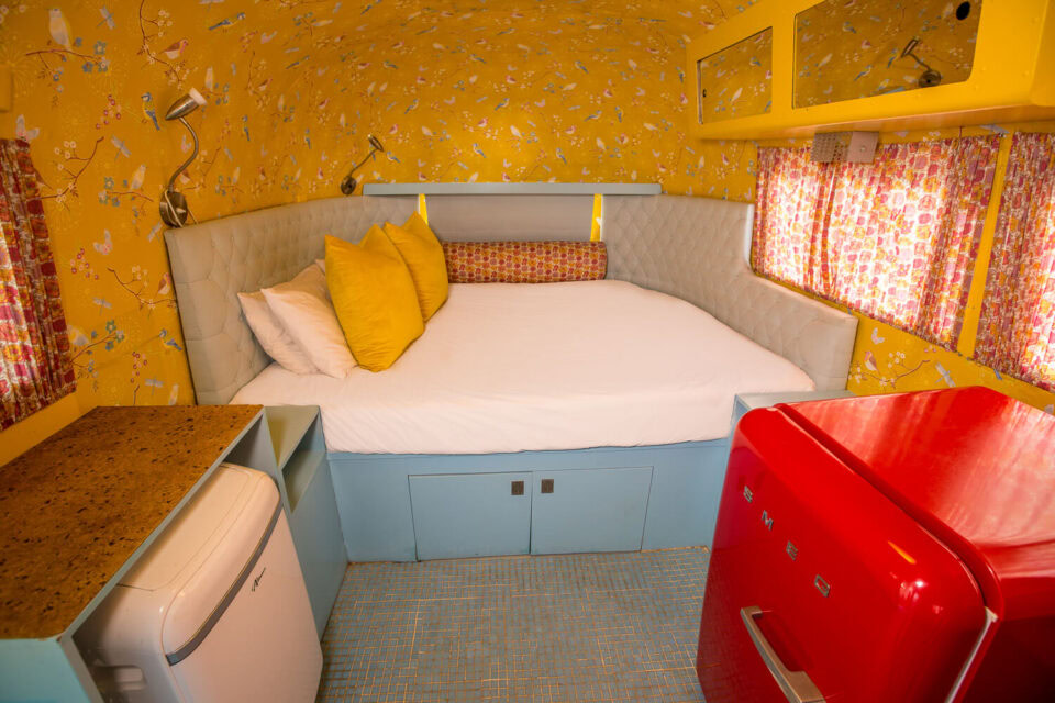 Birdy: bed with yellow cushions, bird-print wallpaper and a red SMEG fridge, Old Mac Daddy, Elgin Valley